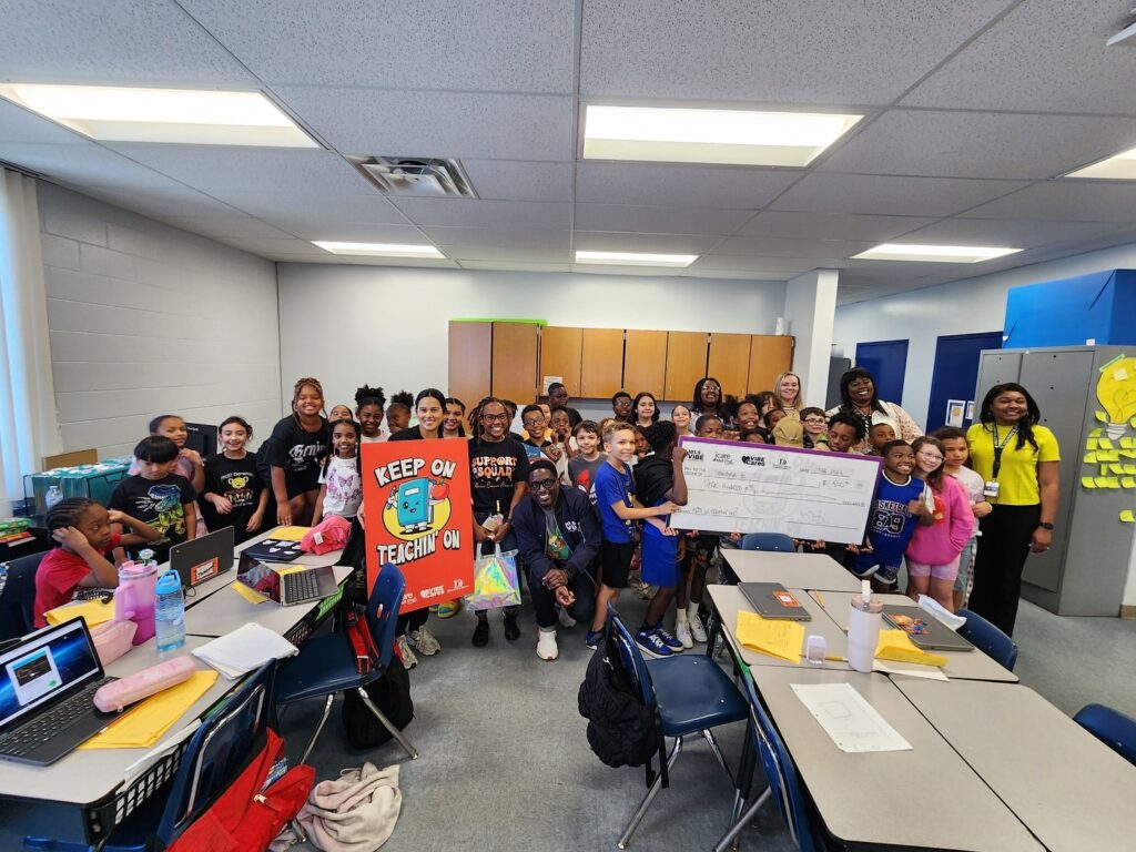 Classroom group with large check and poster.